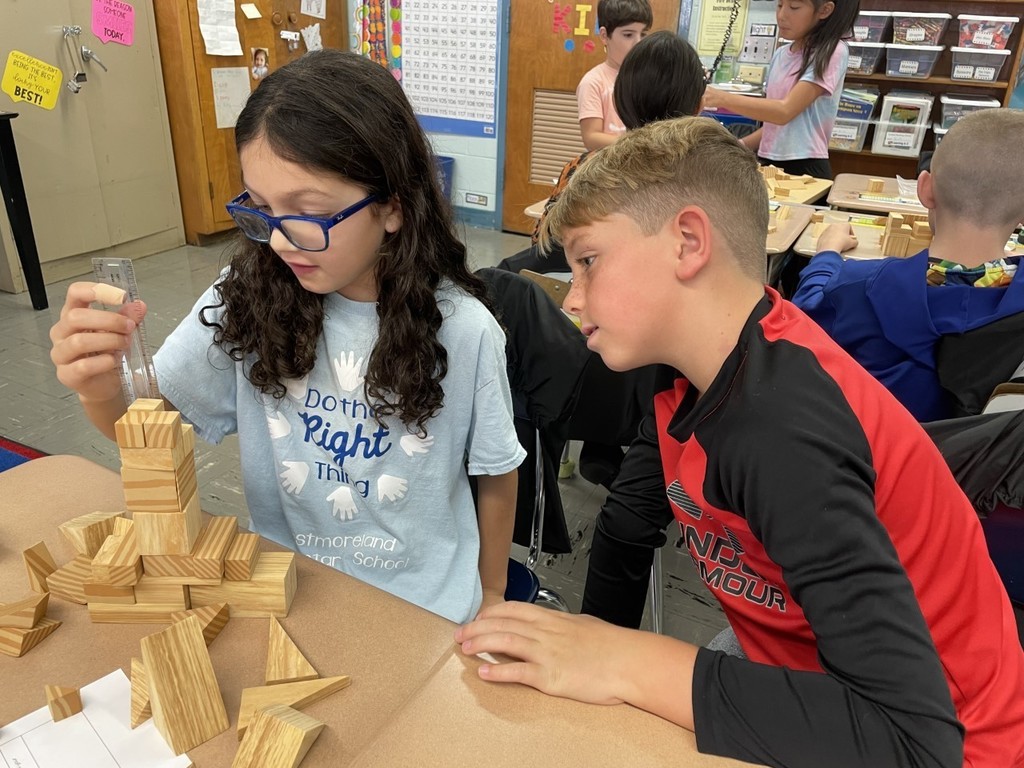Two fourth grade students are using wooden shapes to build a shelter