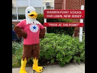 large eagle mascot stands outwith of the school in front of the building sign
