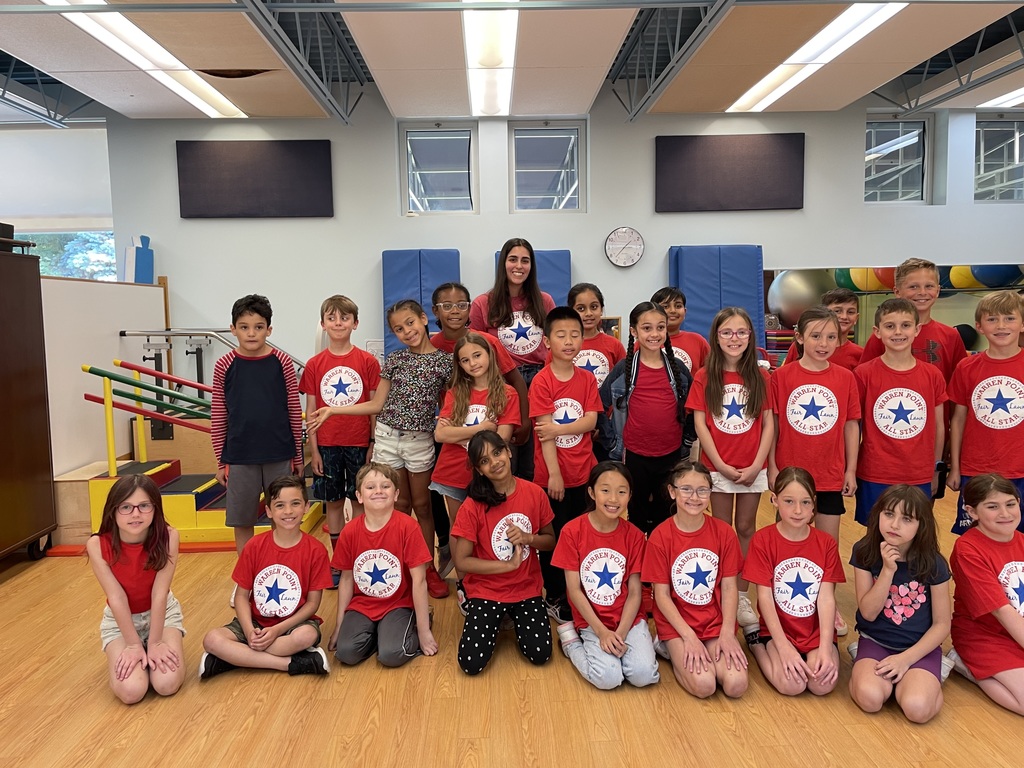 Third grade students and teacher wearing red shirts posing for a photo in a school gymnasium. 